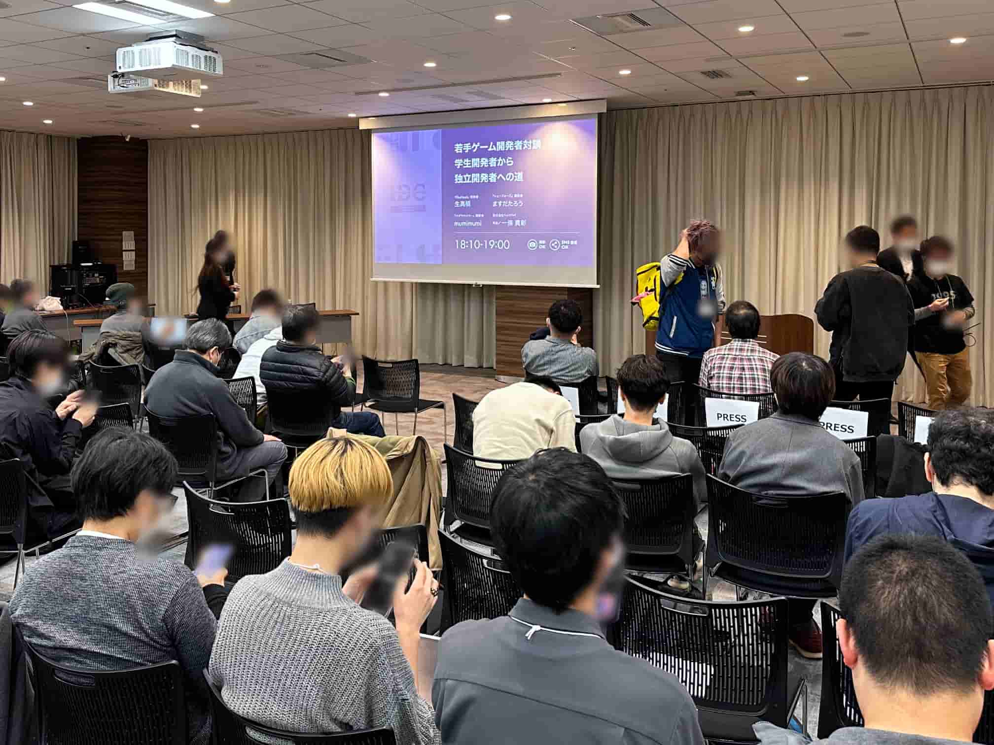 Attendees at the Indie Developers Conference 2023 sitting in a presentation room, watching a slide projected on the screen ahead